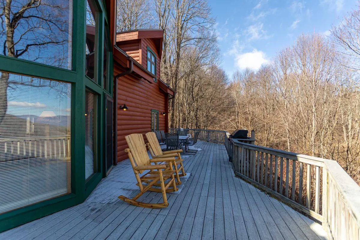 A wooden deck with classic rocking chairs facing out toward the surrounding trees. The atmosphere is tranquil and intimate, ideal for quiet evenings spent enjoying nature or sharing a glass of wine under the stars.